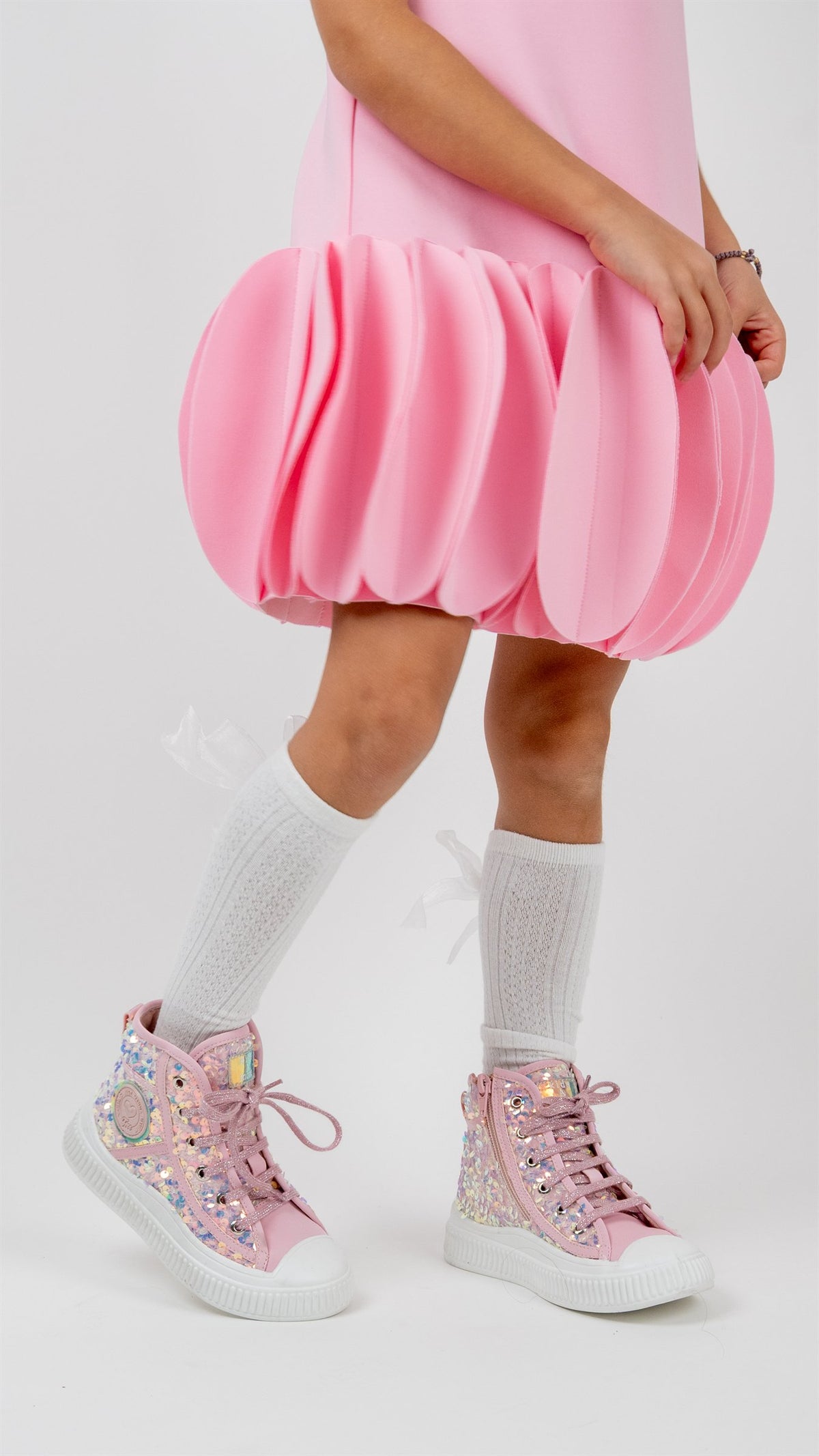 Girl in a pink dress wearing sparkly high-top sneakers