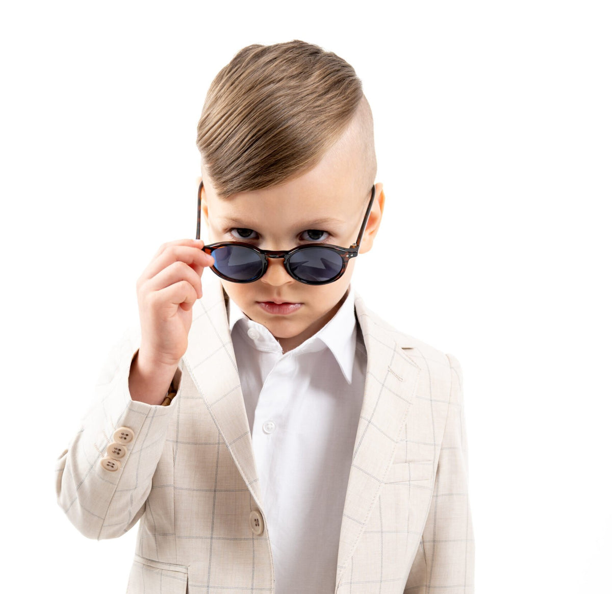 Boy in a beige suit wearing Looklight children's sunglasses